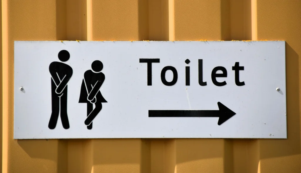 A funny toilet sign with male and female symbols pointing direction outdoors.